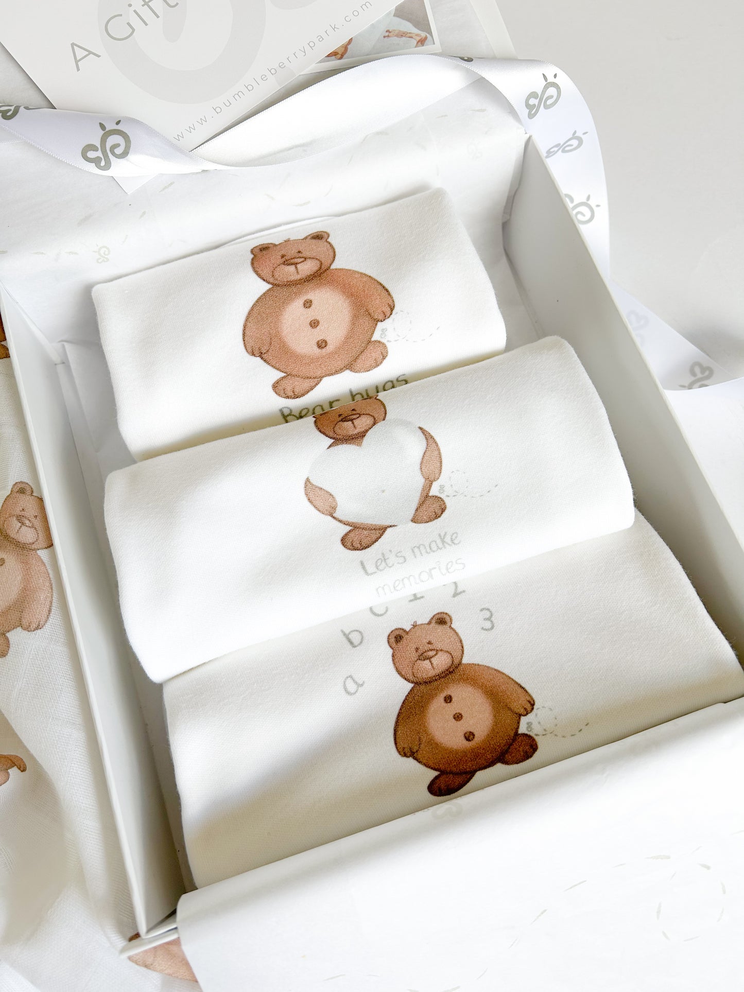 close up of three baby vests with cute brown bear print inside a keepsake memory box for new baby gift