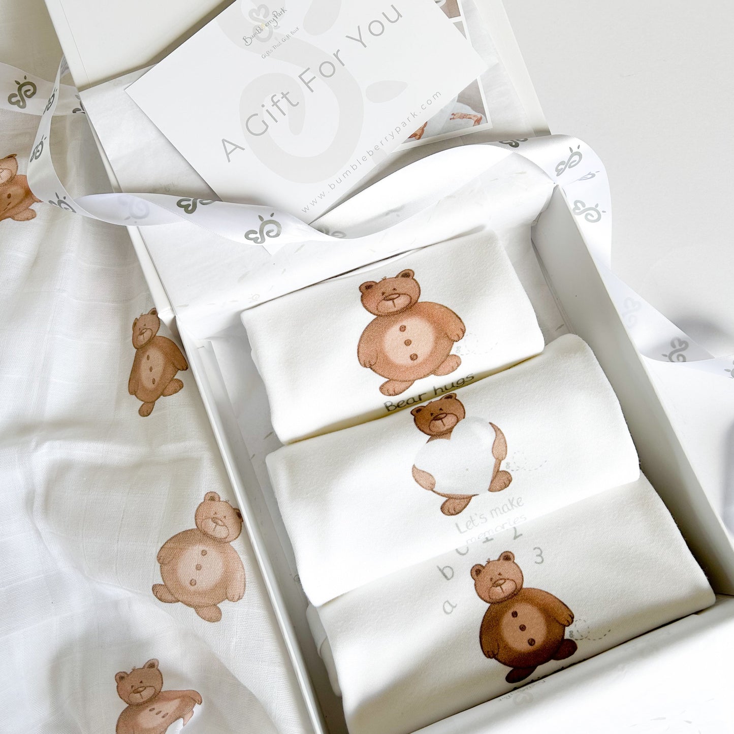 set of 3 mixed size baby bodysuits with cute teddy bear design and inspiring quotes for new parents and babies inside a luxury white gift box with satin ribbon