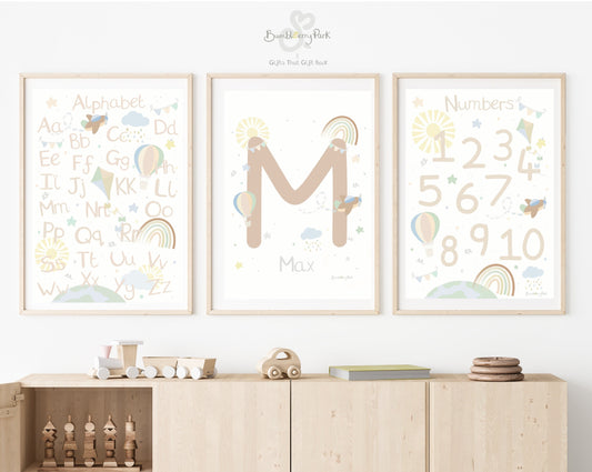 set of three matching alphabet and number posters for children's bedroom. Neutral nursery decor prints with personalised initial letter and name print, with travel and transport theme decor with rainbows, sunshine, hot air balloon and aeroplane features