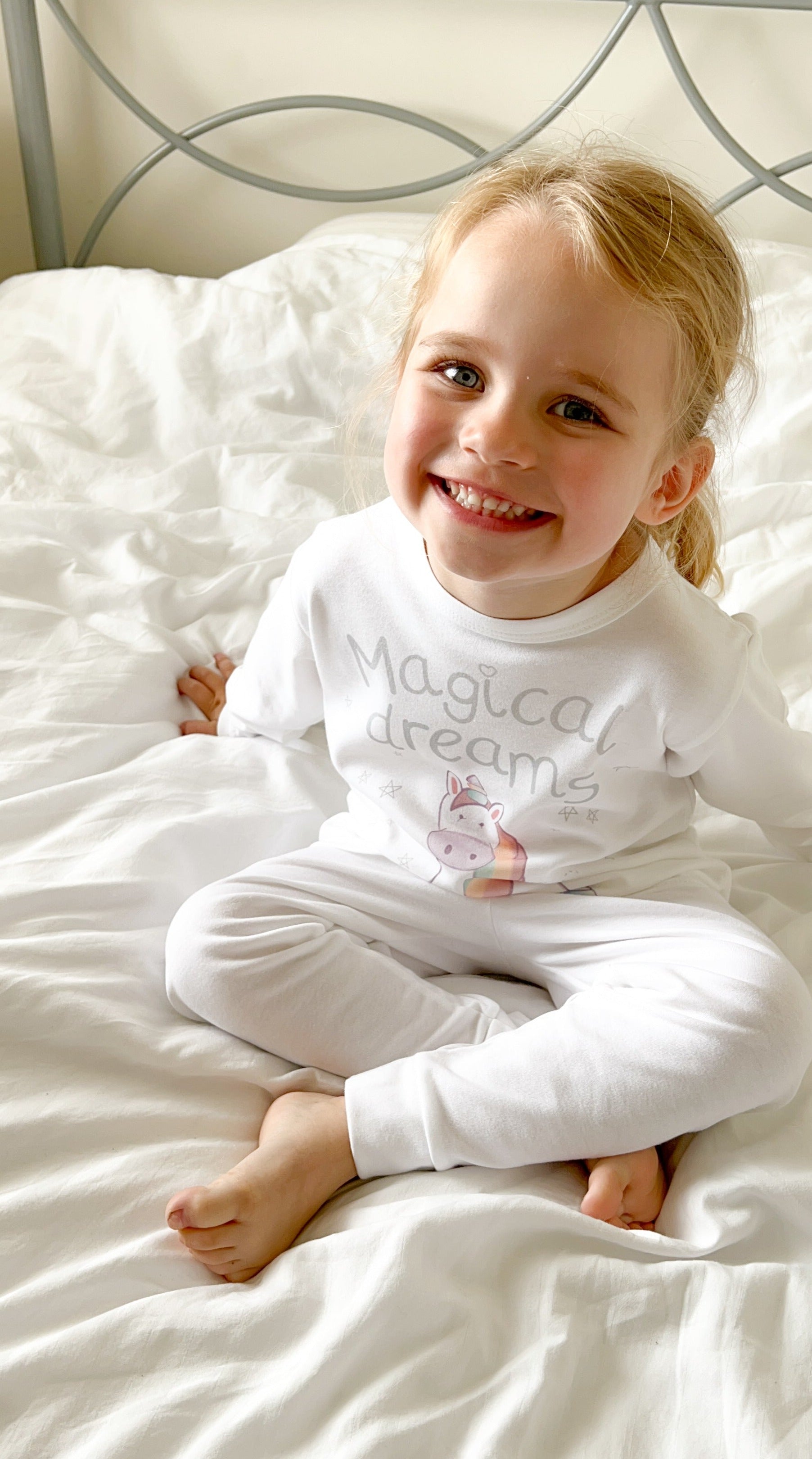 toddler girl wearing unicorn pyjamas with magical dreams quote print