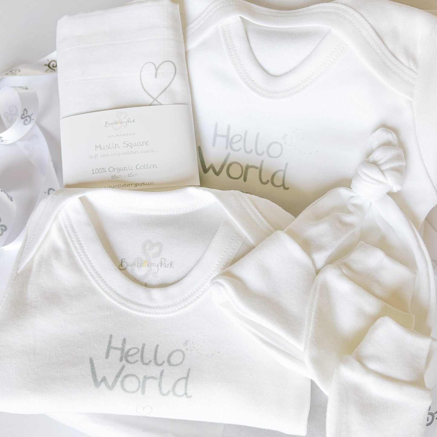 neutral soft grey organic cotton new baby clothing gift set with luxury gift hamper placed inside a white gloss gift box with tiissue paper gift wrapping