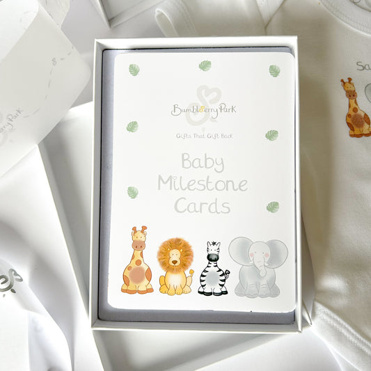 close up gift set of safari animal baby milestone cards including a giraffe, lion, zebra and elephant in a white gift box with ribbon