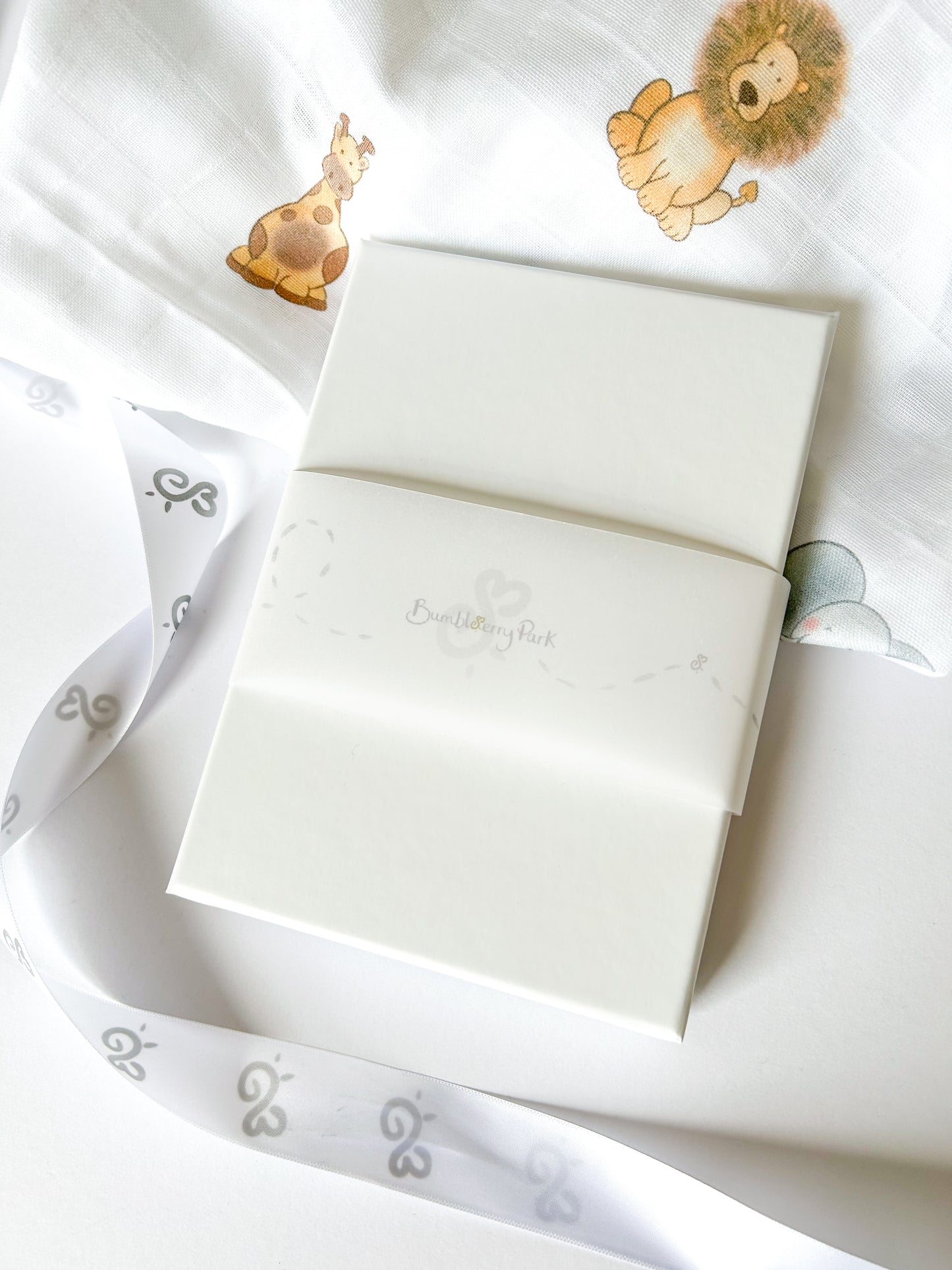 luxury white gift box with a bumbleberry park branded ribbon and safari animal muslin cloth draped behind