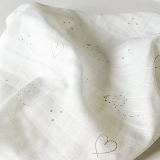 close up on organic cotton white muslin square with silver delicate details of hearts stars and dots and bees