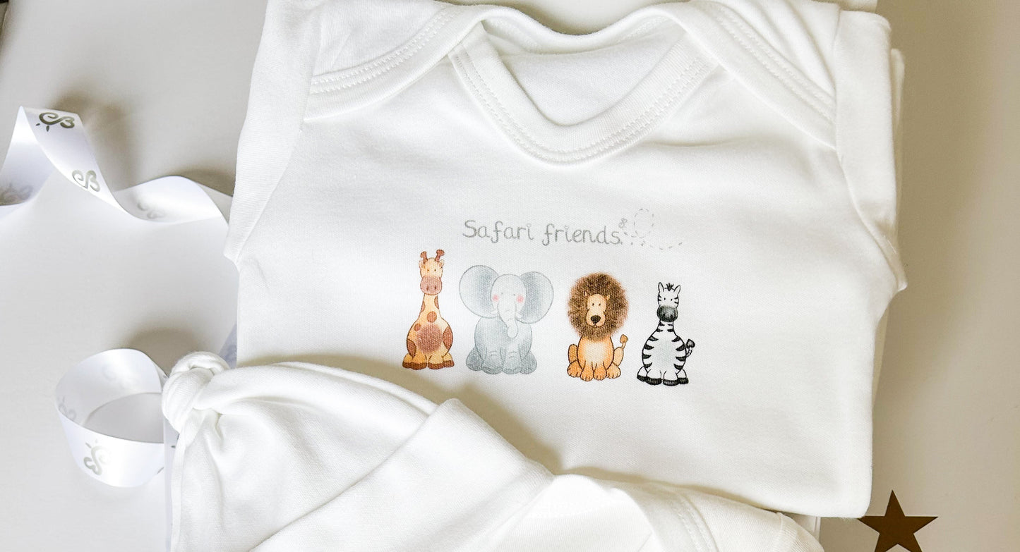close up of white baby sleepsuit with safari animal printed design with giraffe elephant lion and zebra
