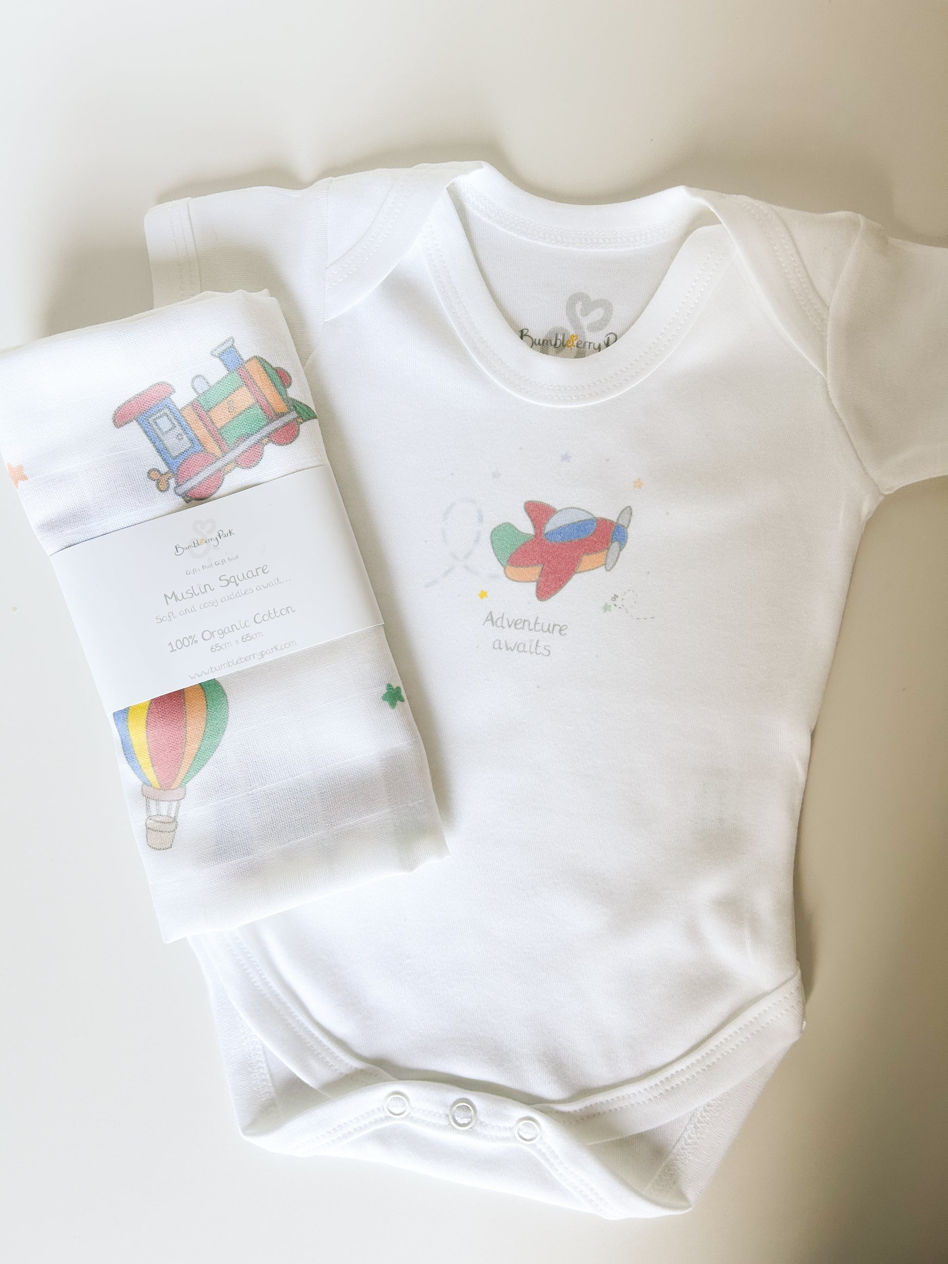 gift set of baby bodysuit and muslin cloth with travel and transport theme print in bright primary colours