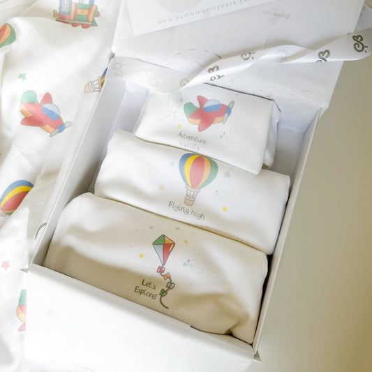 set of three mixed size baby bodysuits with travel and little explorer designs in a luxury white gift box
