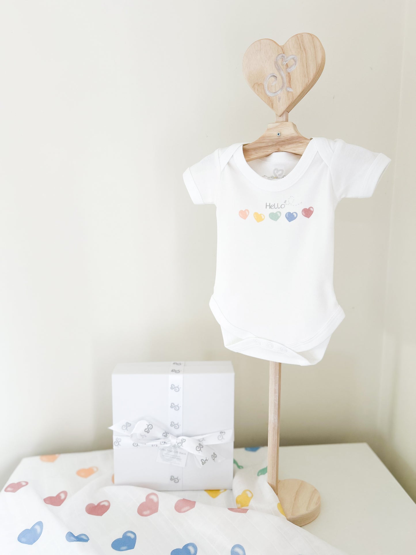 baby bodysuit printed with colourful heart print with a matching baby muslin and gift box set