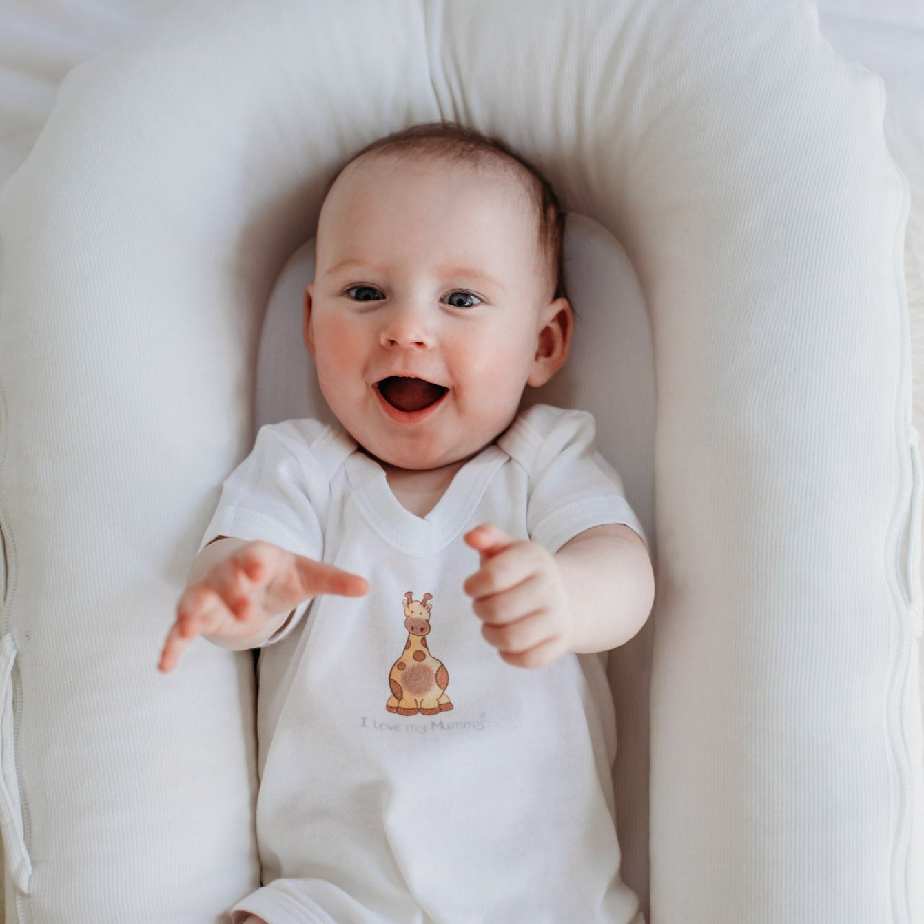 newborn baby wearing an organic white baby bodysuit with a "I love my mummy" safari giraffe design