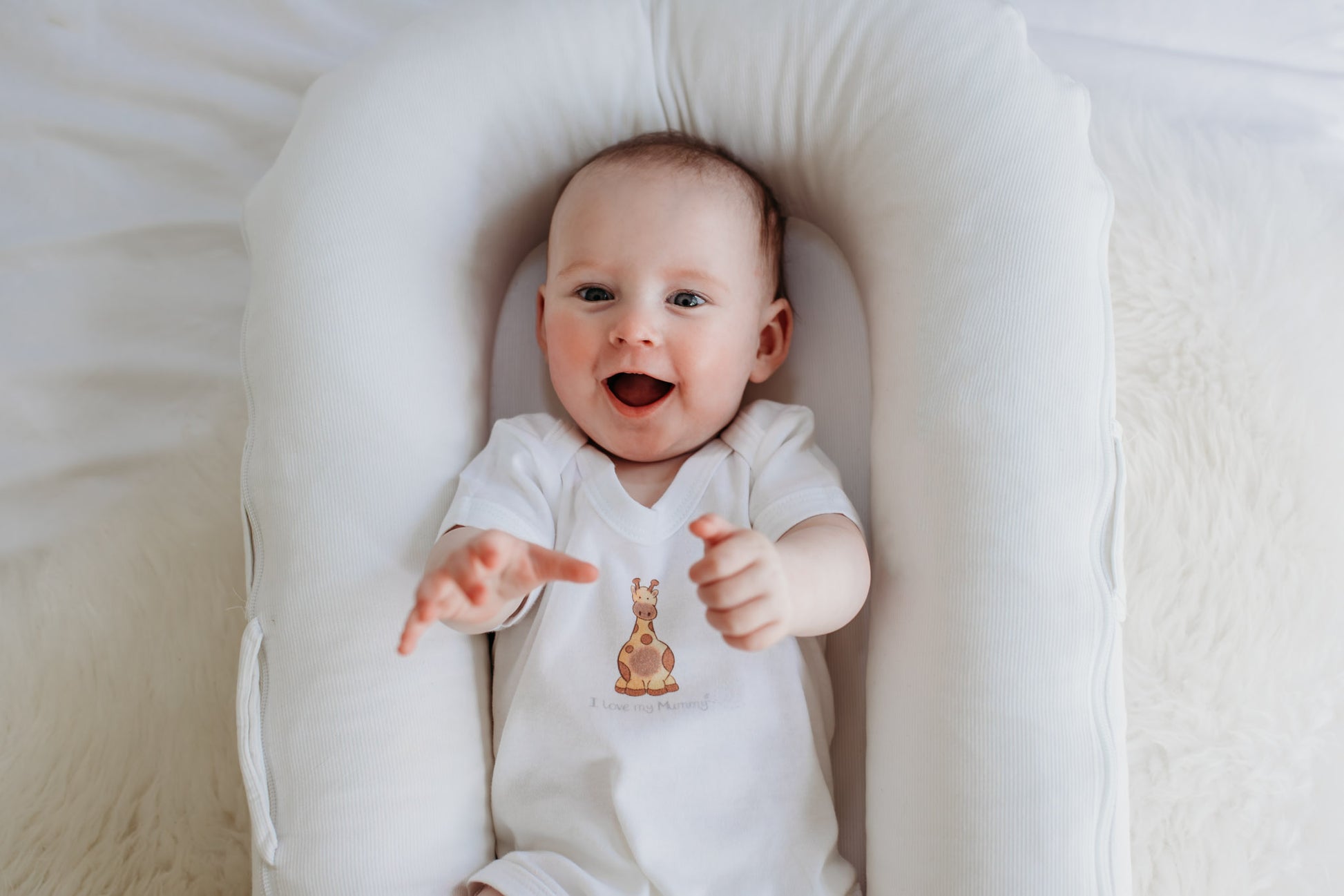 cute baby giggling wearing a white bodysuit with safari giraffe print