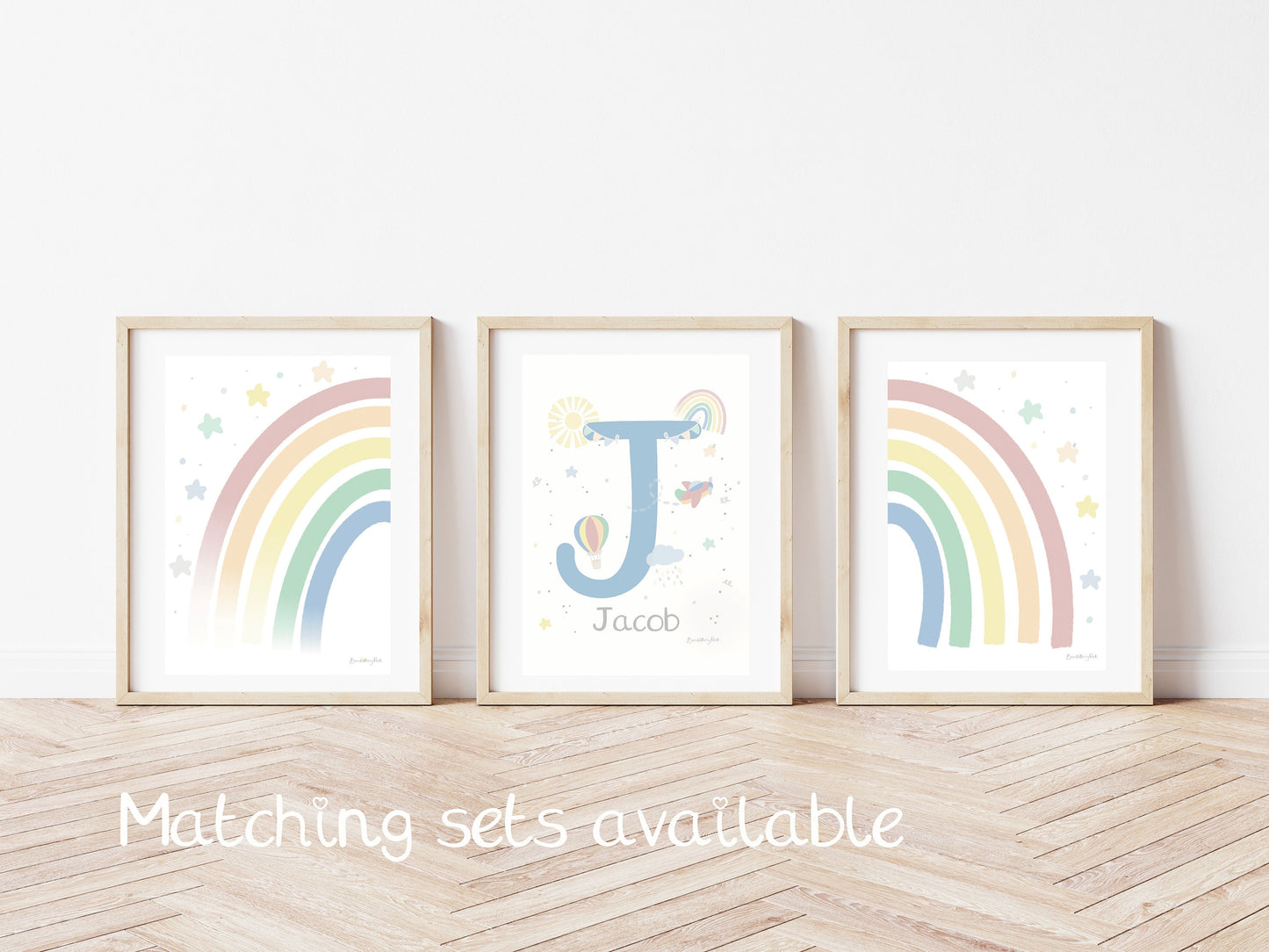 set of three bright pastel wall prints on a children;s bedroom with rainbow and name and initial scandi illustrations